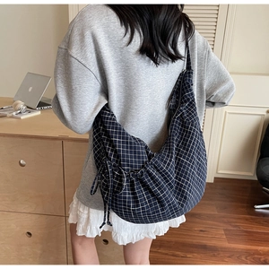 Detail of a large navy blue checkered canvas crossbody bag with drawstring side knots