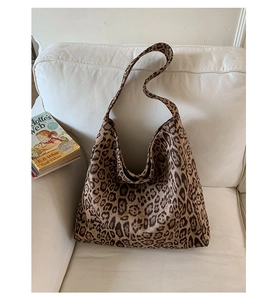 Vista dettagliata della borsa hobo leopardata appoggiata su un divano in tessuto bianco