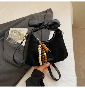 Détail du sac bandoulière noir avec poignée noeud en cuir et pompon en perles colorées