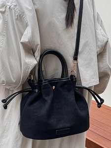 Minimalist black bucket bag with drawstring and top handle in premium matte finish