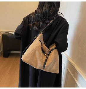 Detailed macro view of khaki suede tote bag texture with black leather strap and gold buckle