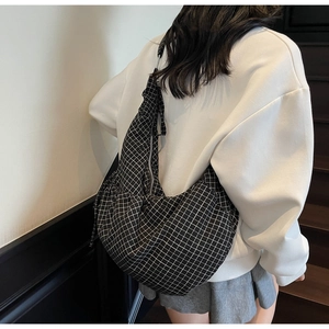 Close-up of black and white checkered crescent shoulder bag with silver zipper closure