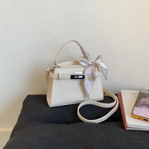 Detail of cream white leather bag with lychee texture and silk scarf handle decoration