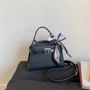 Detail of black pebbled leather handbag with silver twist lock and decorative silk scarf