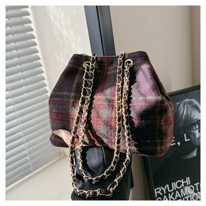 Detail of vintage tartan woolen bag with gold chain strap in artistic indoor lighting