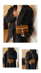 Detail view of a vintage brown crossbody bag with silver zipper and charm on model