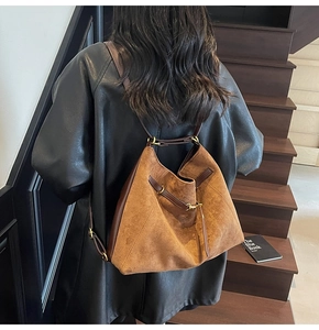 Close-up of retro brown suede tote bag with leather strap and golden metal buckle details