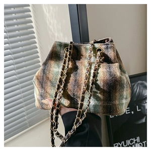 Detailed close-up of retro plaid wool bucket bag with gold metal chain strap in natural light