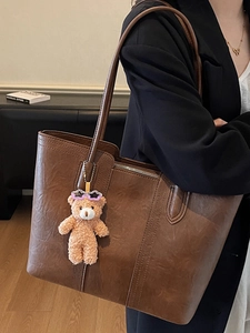 Vintage brown leather tote bag with cute plush bear charm and decorative stitching detail