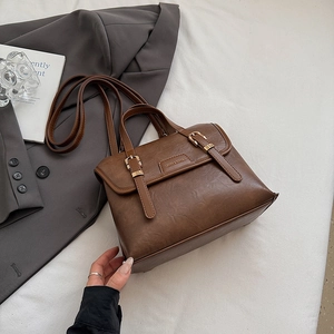 Detailed close-up of retro brown PU leather messenger bag with decorative metal buckles