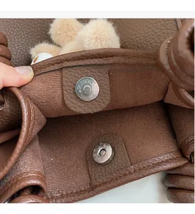 Close-up of magnetic snap closure on brown litchi leather tote bag with fabric lining