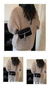 Close-up of black crossbody box bag with silver robot charm and metallic zipper