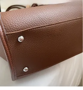 Close-up of caramel brown pebble leather tote bag base with silver protective metal feet