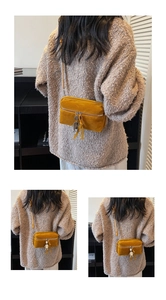 Detail of mustard yellow suede crossbody bag featuring a cute metal robot charm pendant