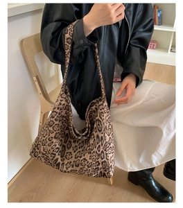 Dettaglio della borsa hobo in tela leopardata portata a spalla in un interno
