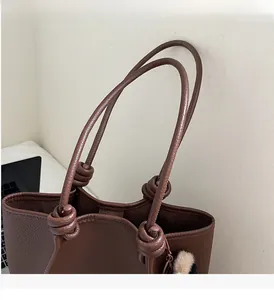 Detail of dark brown lychee leather tote with unique knotted handle design and soft texture
