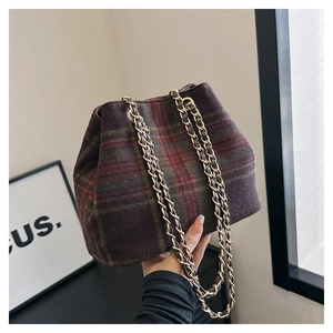 Detail of vintage plaid wool bag with elegant gold chain strap for autumn style