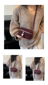 Close-up detail of burgundy suede crossbody bag with silver fringe zipper and metal charms