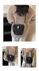 Detail of black suede bucket bag with gold metal buckle and adjustable shoulder strap