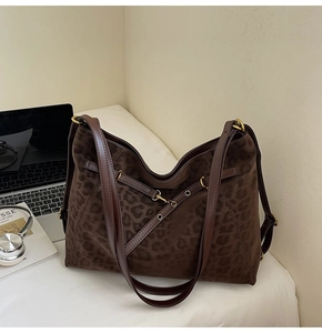 Detail view of leopard print tote bag with brown leather straps and vintage gold hardware