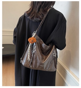 Detail of vintage brown shoulder bag featuring star zippers and a teddy bear pendant