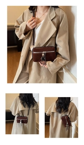 Detail view of brown suede crossbody bag with silver zipper and robot charm accessory