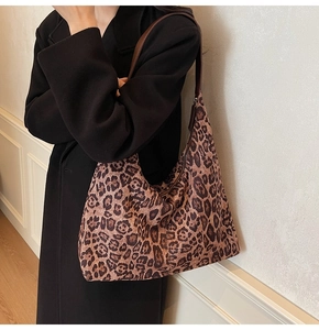 Detailed side view of a large leopard print tote bag with brown leather strap worn by a model