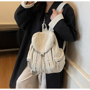 Detalle de la mochila de nailon blanco crema con cierre de cordón y solapa superior