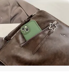 Close-up of brown leather bag with star-shaped silver zipper and side pocket detail