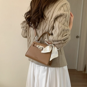 Detailed back view of a brown pebbled leather shoulder bag with silk scarf on handle