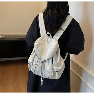 Detalle de la mochila color blanco crema con cierre de cordón y textura de tela plisada