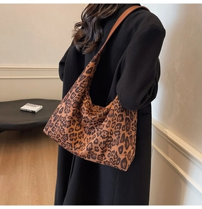 Detail of leopard print tote bag with brown leather strap worn by a model in interior