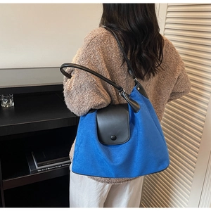 Detail view of Klein blue tote bag showing contrast black leather strap and button closure