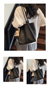 Detail of black pebbled leather tote bag featuring a knotted handle and cute bear charm