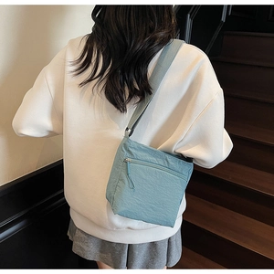 Light blue nylon crossbody bag shown from behind, featuring a minimalist casual style