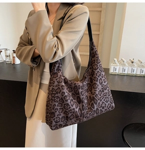 Detailed view of leopard print tote bag with black leather strap on a female model