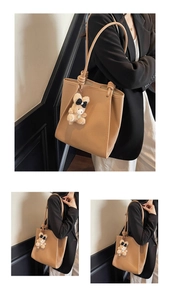 Detail of camel leather tote bag with lychee texture and cute plush bear charm