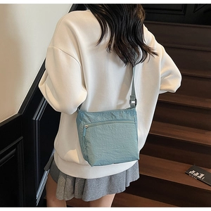 Detail of light blue nylon crossbody bag with pleated texture worn on model's back