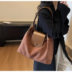 Detail view of large brown suede shoulder bag featuring a stylish contrast leather flap
