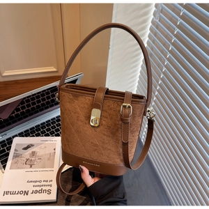 Detailed macro of brown suede bucket bag featuring quilted stitching and a gold swivel lock