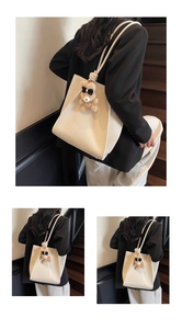 Detail of off-white lychee grain tote bag with plush bear charm and side fold design