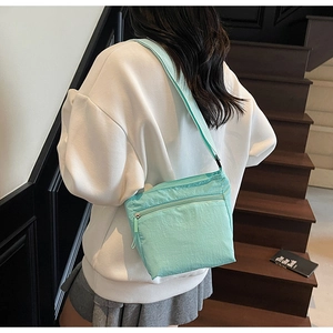 Detail of mint green nylon crossbody bag showing crinkled texture and adjustable strap