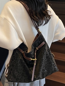 Large leopard print tote bag with brown leather trim and golden metal clasp on model