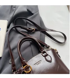 Deep chocolate glossy leather handbag with adjustable strap on professional suit background