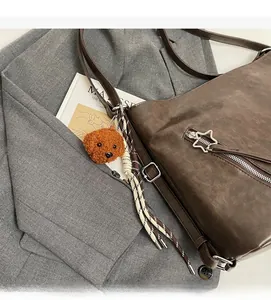 Detail of vintage brown PU leather bag featuring star zipper and plush teddy bear charm