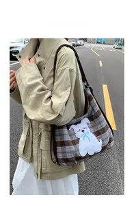 Detailed outdoor view of plaid tote bag featuring a cute white dog patch and brown strap