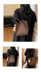 Three-way view of a brown leather tote bag with long knot straps and a cute bear charm