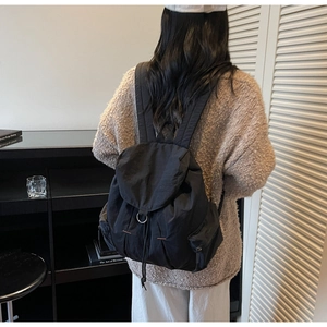 Detalle de mochila de nailon negro con hebilla metálica en D y cierre de solapa
