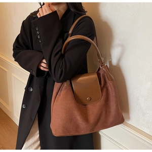 Close-up of a large brown suede tote bag featuring smooth leather trim and round buckle
