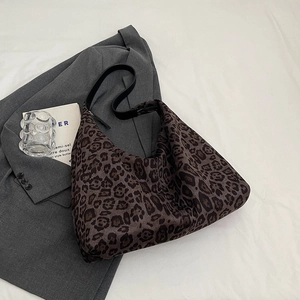 Detail view of leopard print tote bag with black strap on a grey suit background